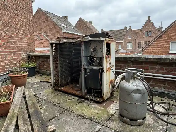 Ancien groupe de climatisation déposé à côté d'une bouteille de récupération